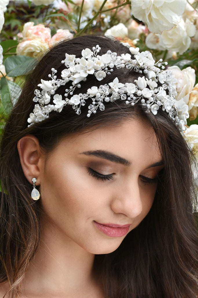 Dark hair bride wears a double row headband of ceramic flowers with a background of white roses