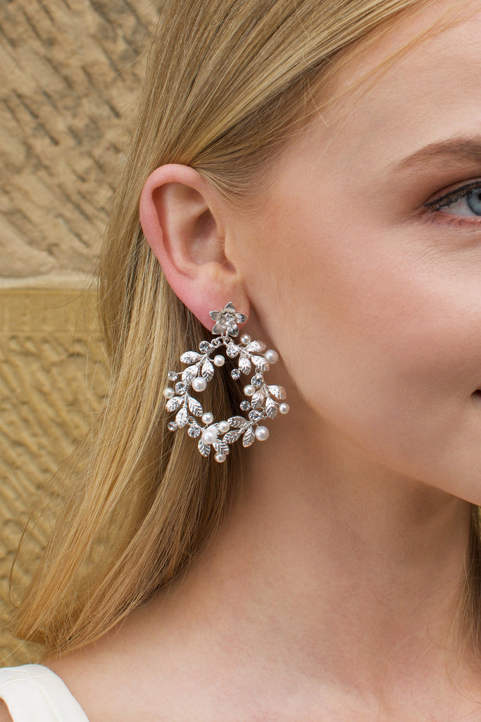 Model with Blonde hair wears a silver hoop shape earring in her ear. 