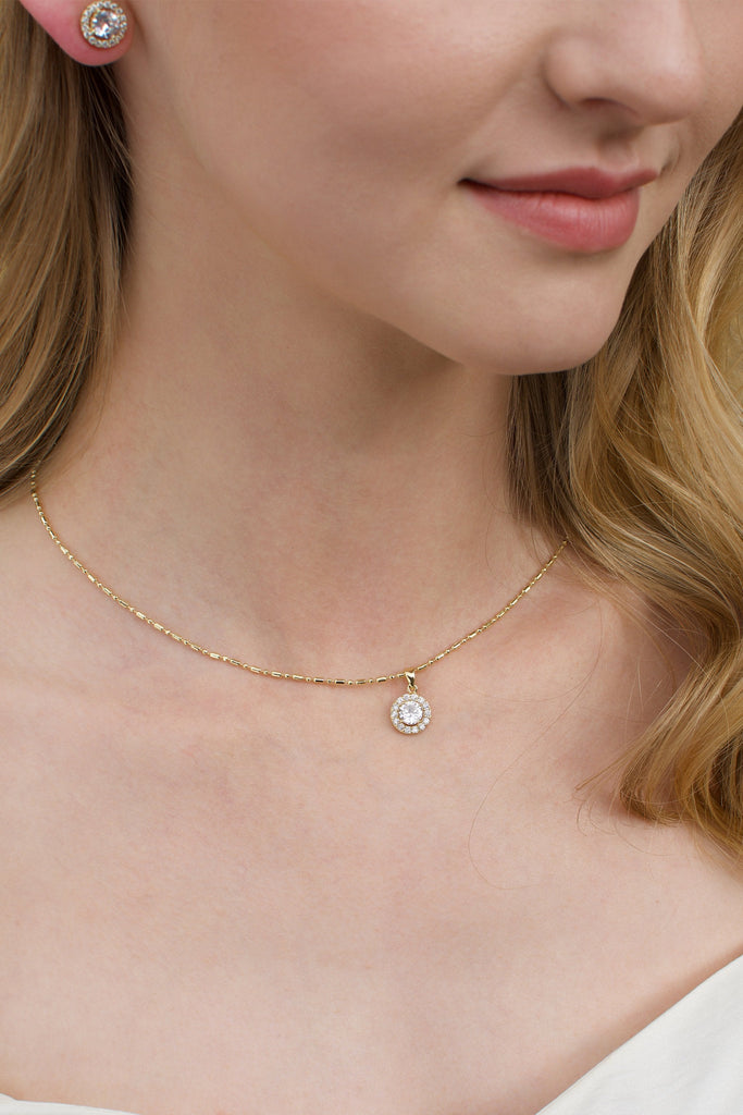 A gold chain around the neck of a model with a single hanging stone