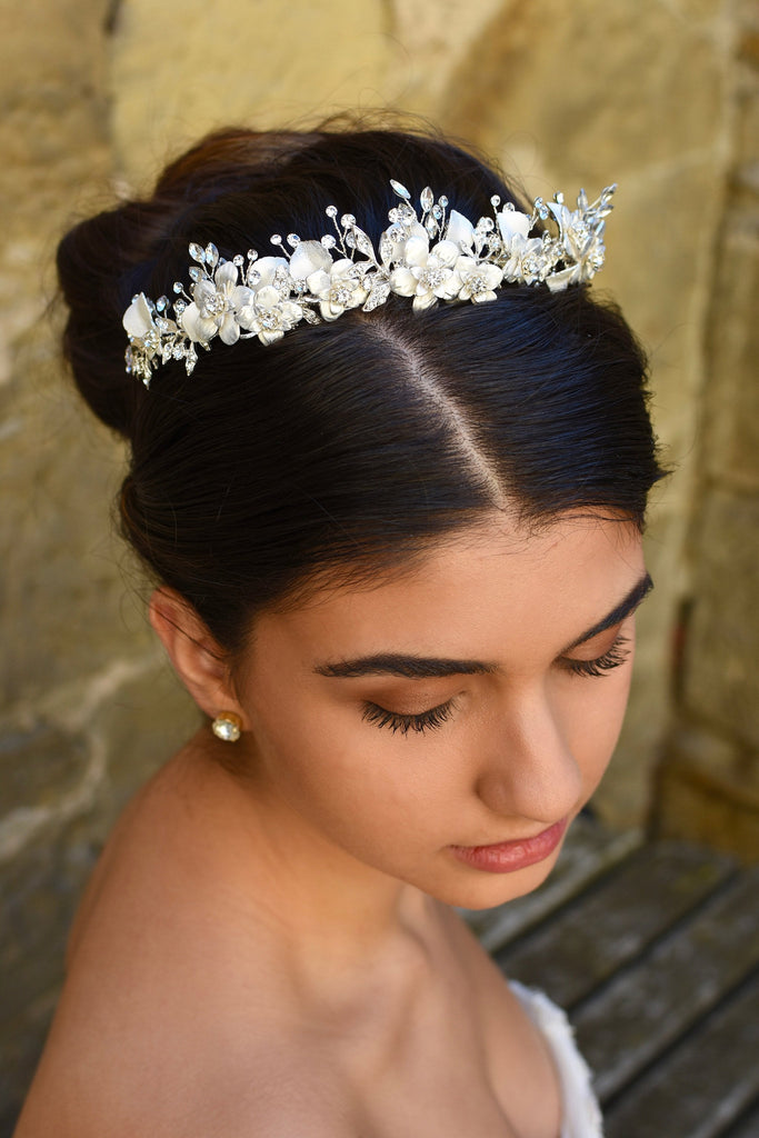 White and silver Bridal headpiece is worn by a dark hair model with a stone wall backdrop
