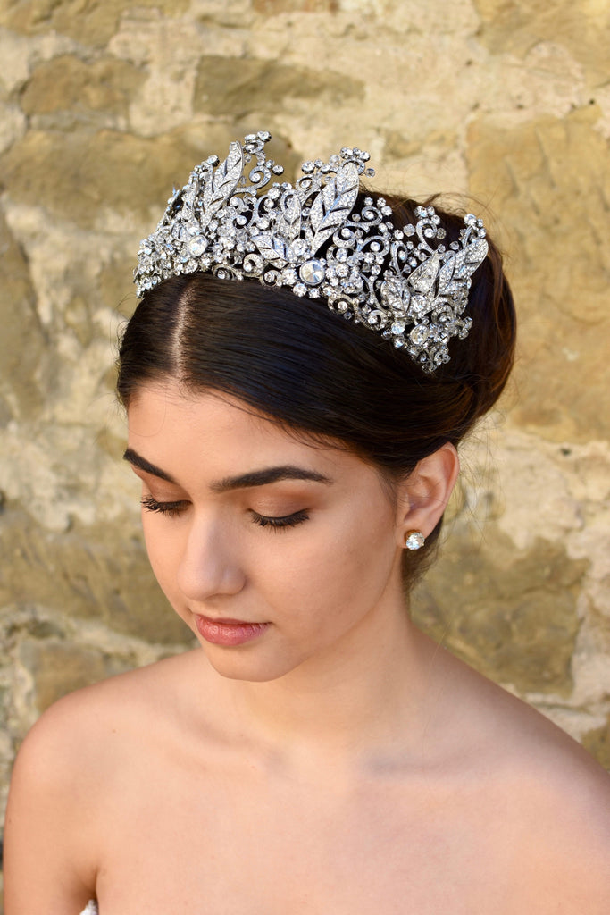 A Tall Bridal Tiara in Silver worn by a Dark Hair Bride with an old stone wall background