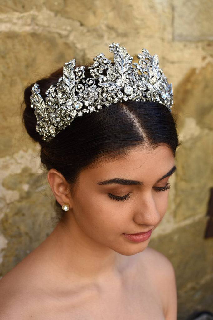 A High Bridal Crown with tall peaks worn by a dark bride with a stone wall backdrop