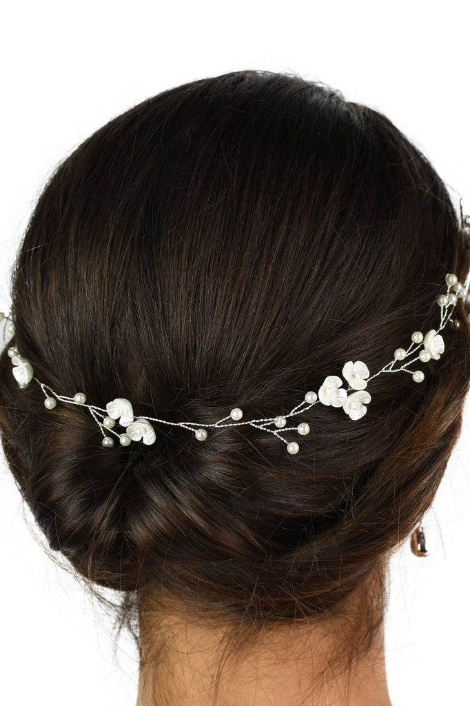 Ceramic Pearl flowers on a thin silver vine worn on a brown hair model with a white background