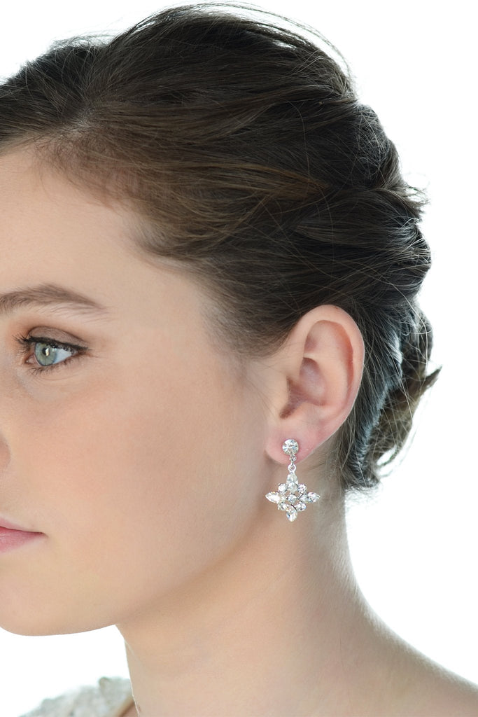 Green eyed dark hair model wears a simple drop earring with a white background