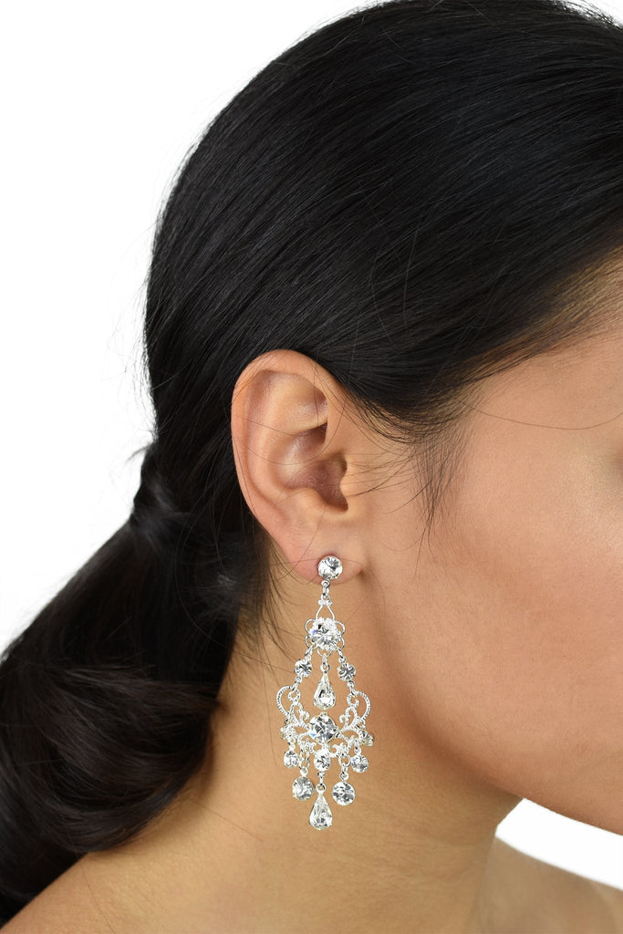 Black haired bride wears a long silver chandelier earring with a white background
