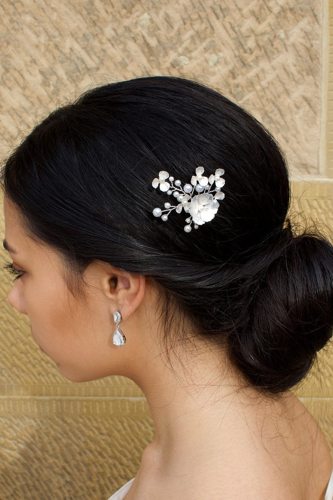 Model Bride wearing a white hair pin in her dark hair with a stone wall background