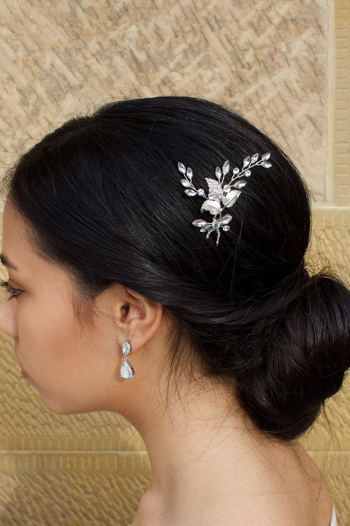 A Dark hair model wears a Silver Bridal Hairpin in the side of her hair with a stone wall background