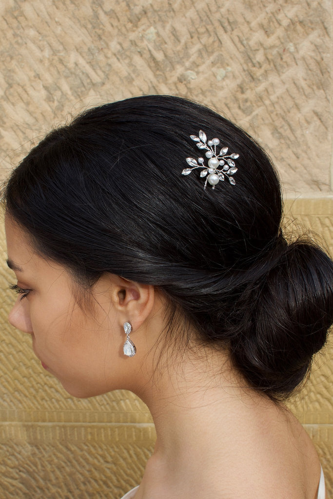A black haired model wears a pearl and crystal hairpin with a sandstone background