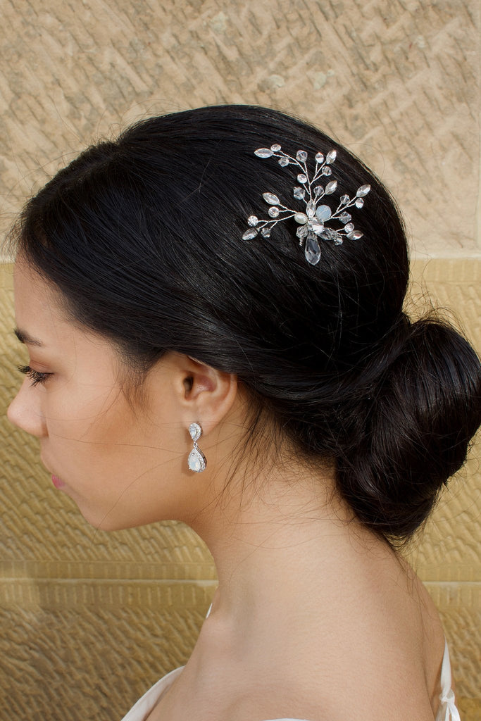 A dark hair Bride wearing a silver hairpin with pearl and white opal with a sandstone wall backdrop