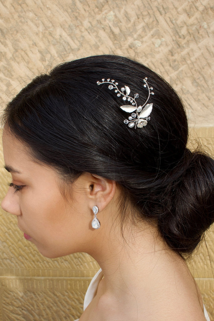 A bride wears a Silver hair pin in her dark hair with a stone wall background