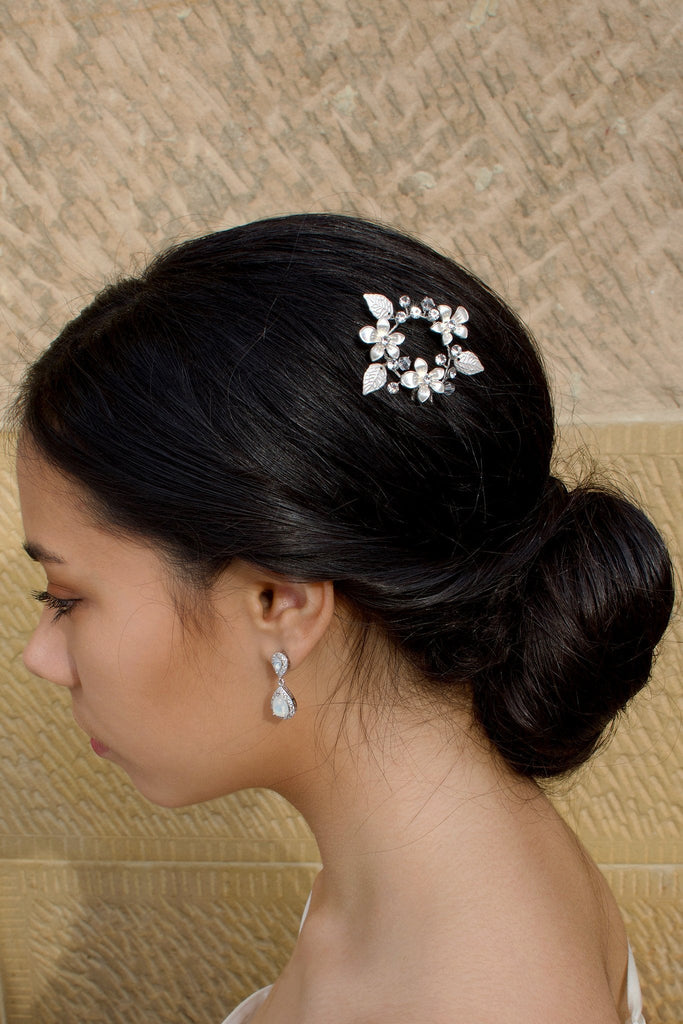 Ring of silver leaves and flowers hairpin worn by a dark hair bride on the side of the head with a sandstone background
