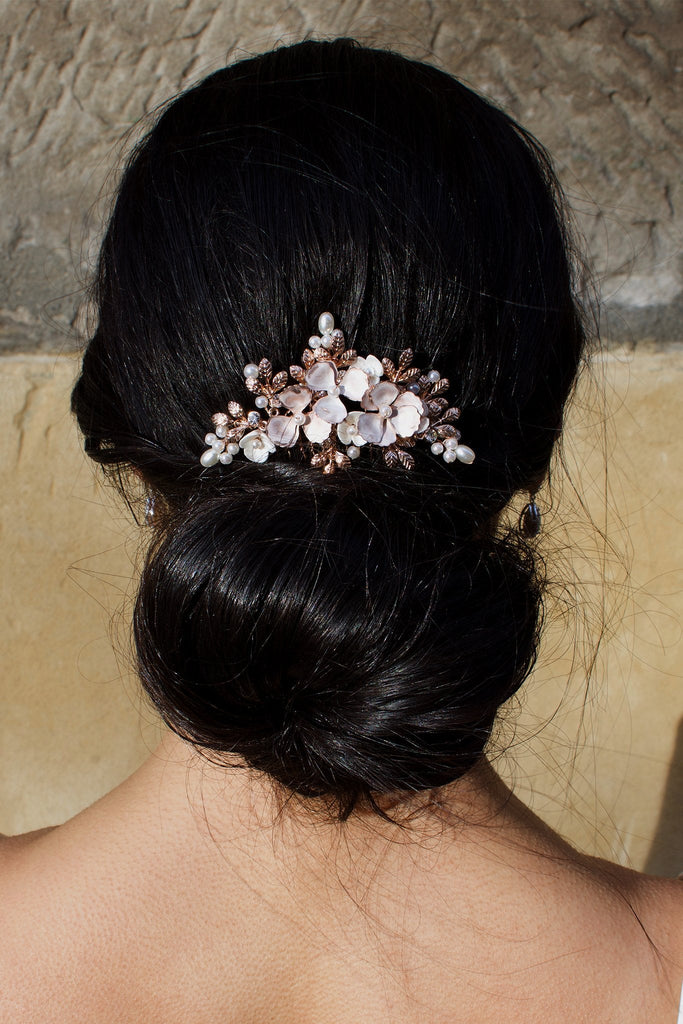 A black hair model wearing a pale rose gold comb above a bun of hair