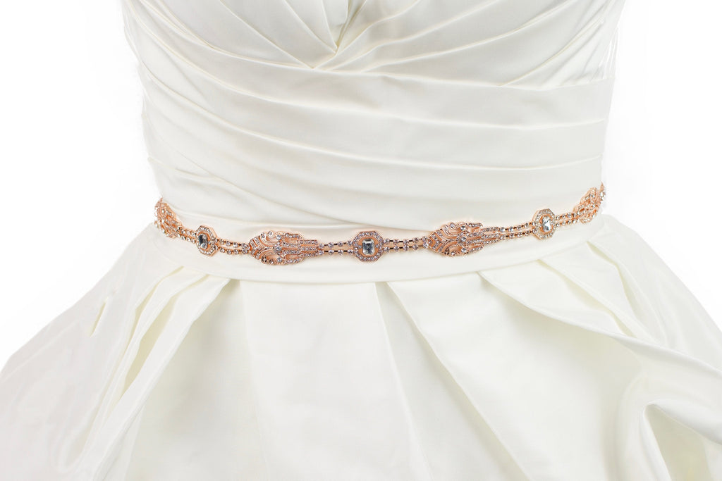 A rose gold narrow bridal belt worn on an ivory bridal gown