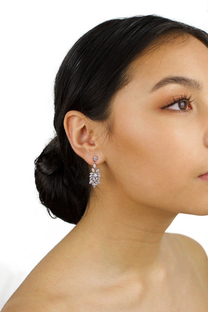 Model wears a silver earring with tiny stones. She has dark hair and a white background