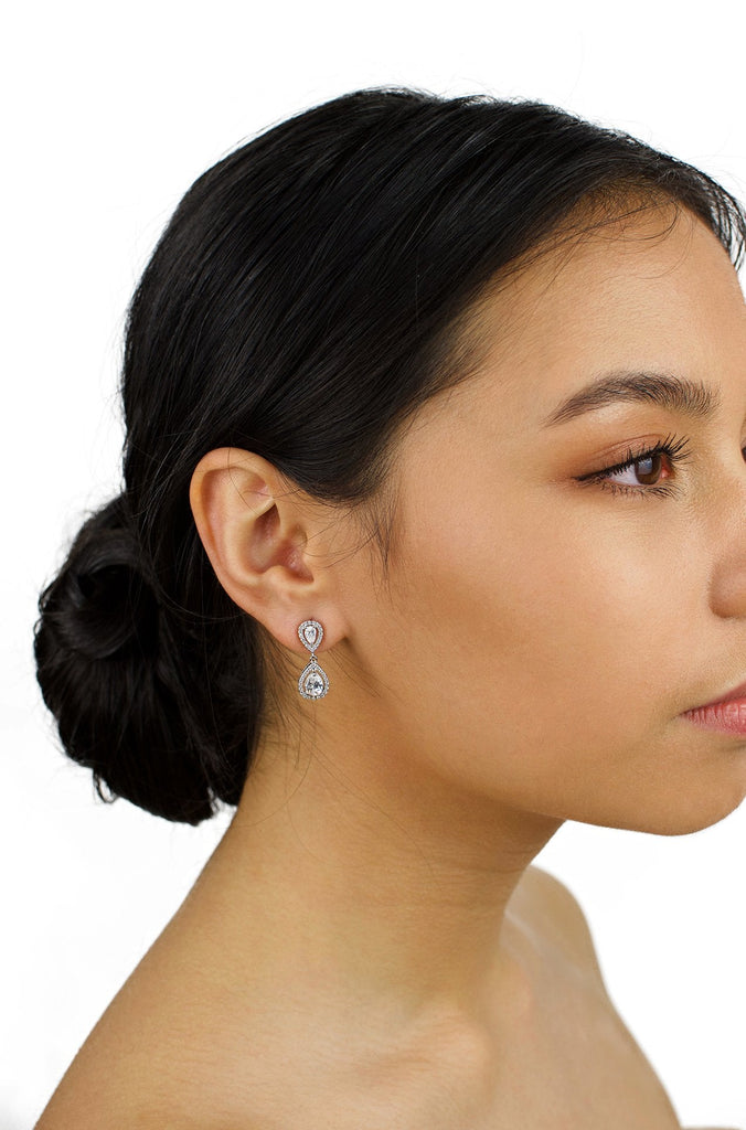 Small silver drop earring worn by a dark hair bride with a white background 