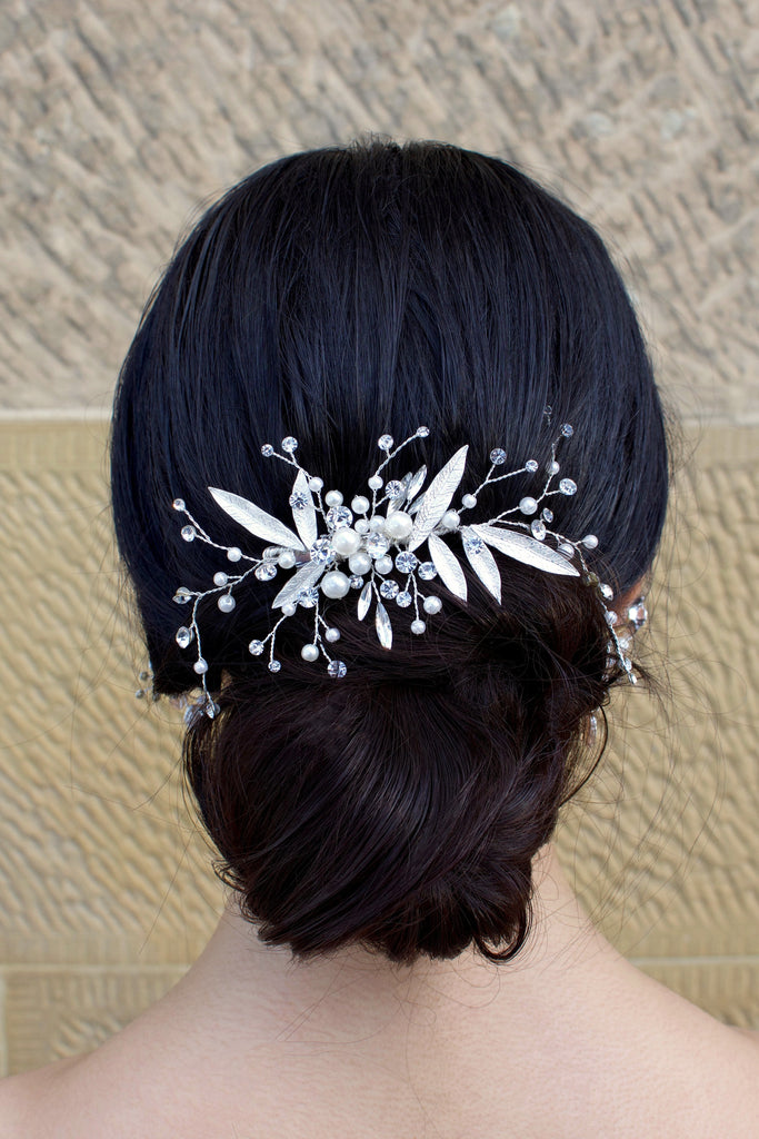 Silver leaf comb at the back of a brides head on dark hair with a stone wall backdrop