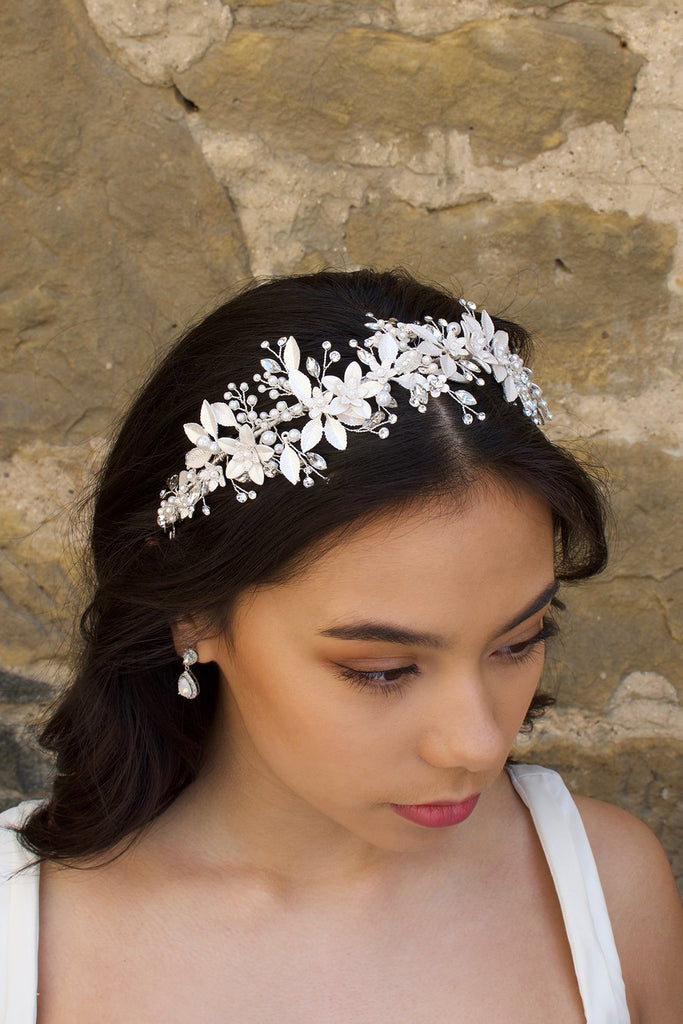 Black haired model wears a silver leaves headband with a wall backdrop
