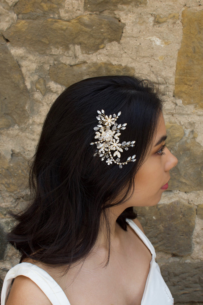 Gold Leaves and Crystals side comb worn by a dark haired model with a stone wall background