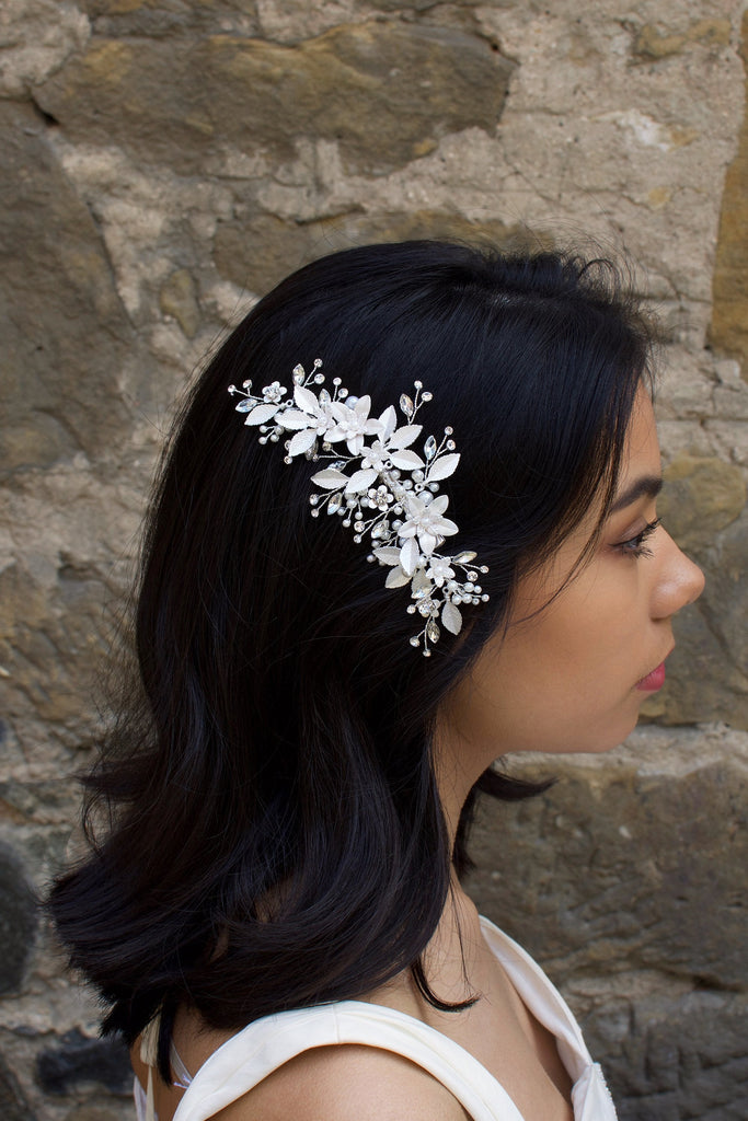 Dark haired model with long hair wears a side comb of silver leaves at the side of her head.