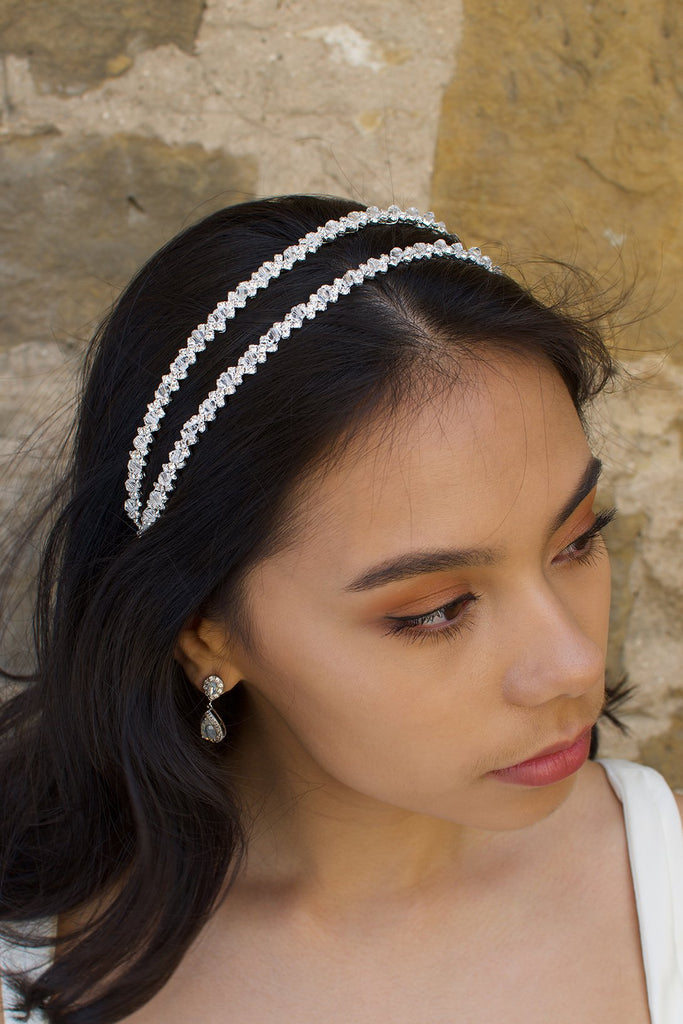 Black hair bride wearing a simple two row silver headband with a stone wall background. 