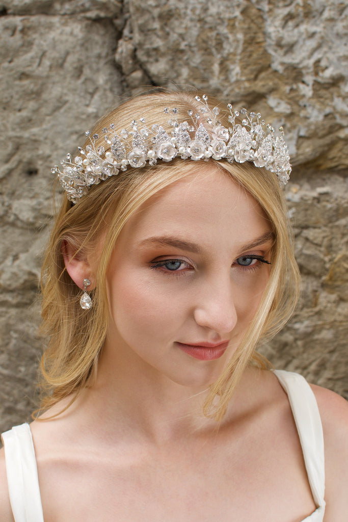 A Silver Flowers and pearls wide tiara worn by a blonde bride with a stone wall background.