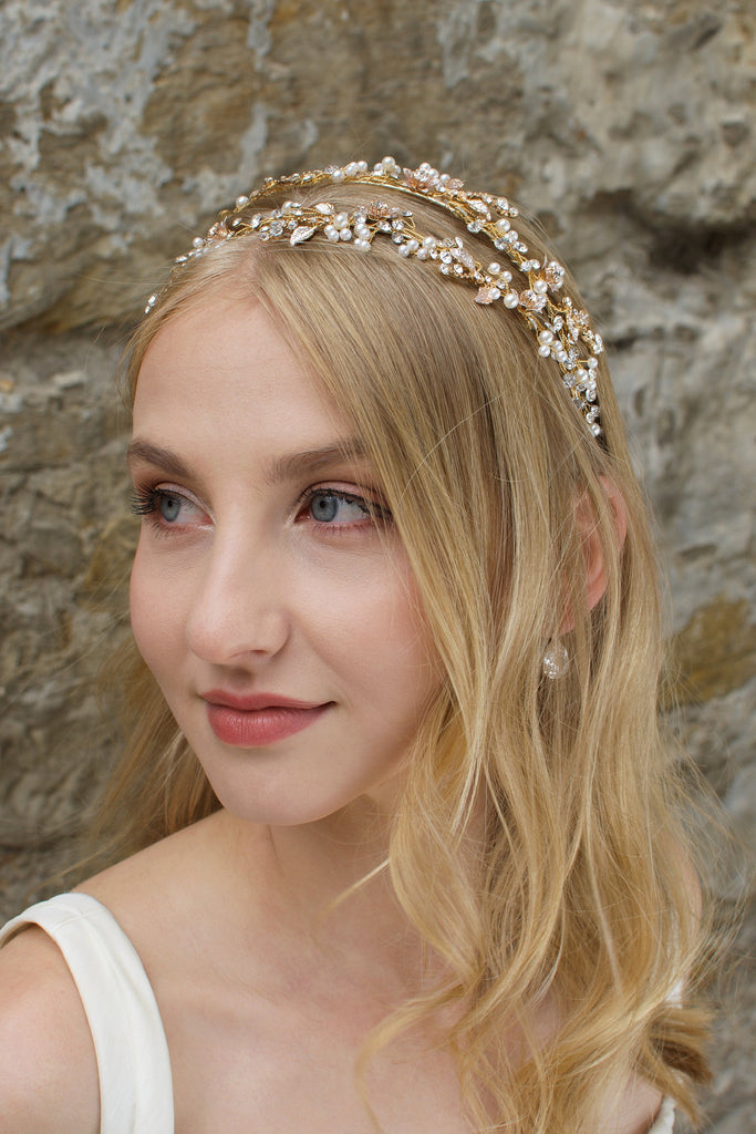 Blonde Bride with green eyes wears a double row bridal headband in gold with a stone wall background
