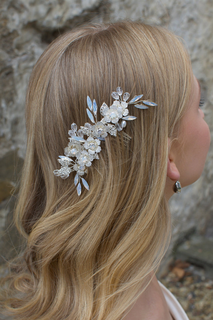 Long Blonde hair Model Bride wears a small white opal comb on the side of her head. There is a stone wall background