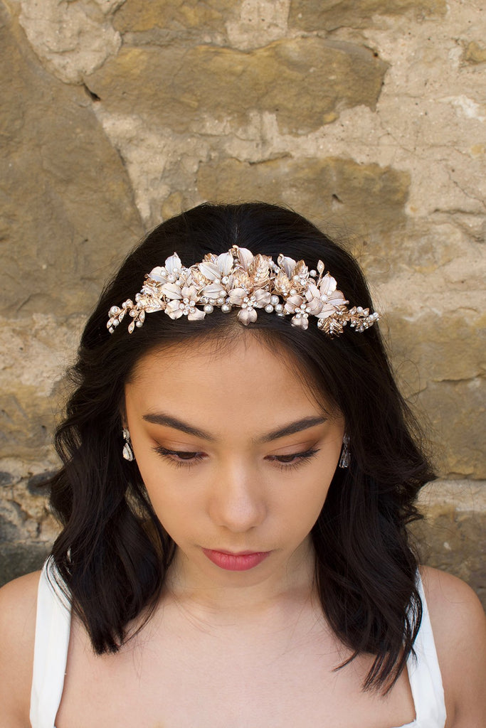 Black haired model wears a pale rose gold and pearl low bridal headband with a stone wall behind