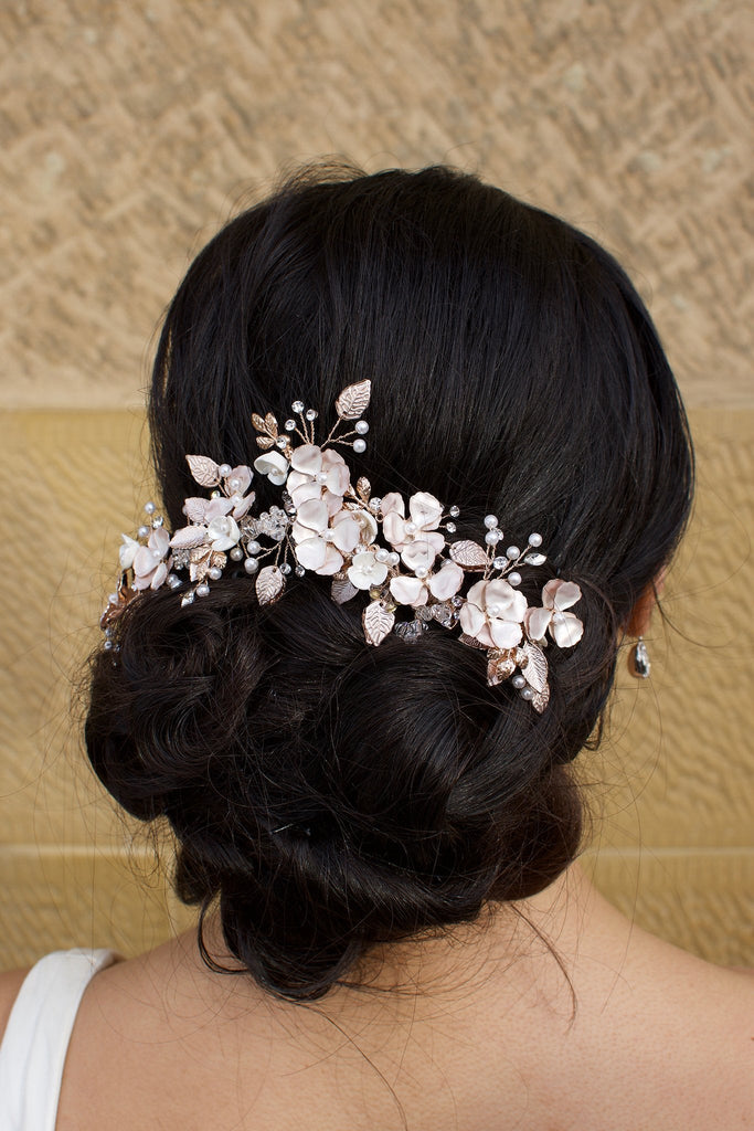 Bride wears a Pale Rose Gold Bridal headpiece in her dark curly hair with a stone wall background