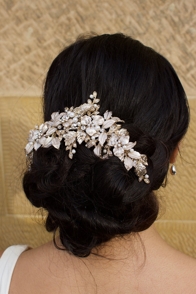 A wide Bridal Headpiece of gold leaves at the back of a model's head with a stone wall backdrop