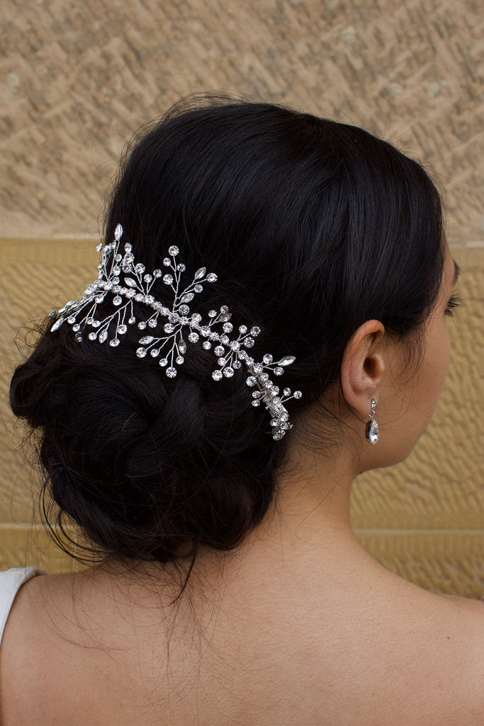 Dark hair model wearing a silver bridal vine around the back of her hair with a sandstone wall backdrop