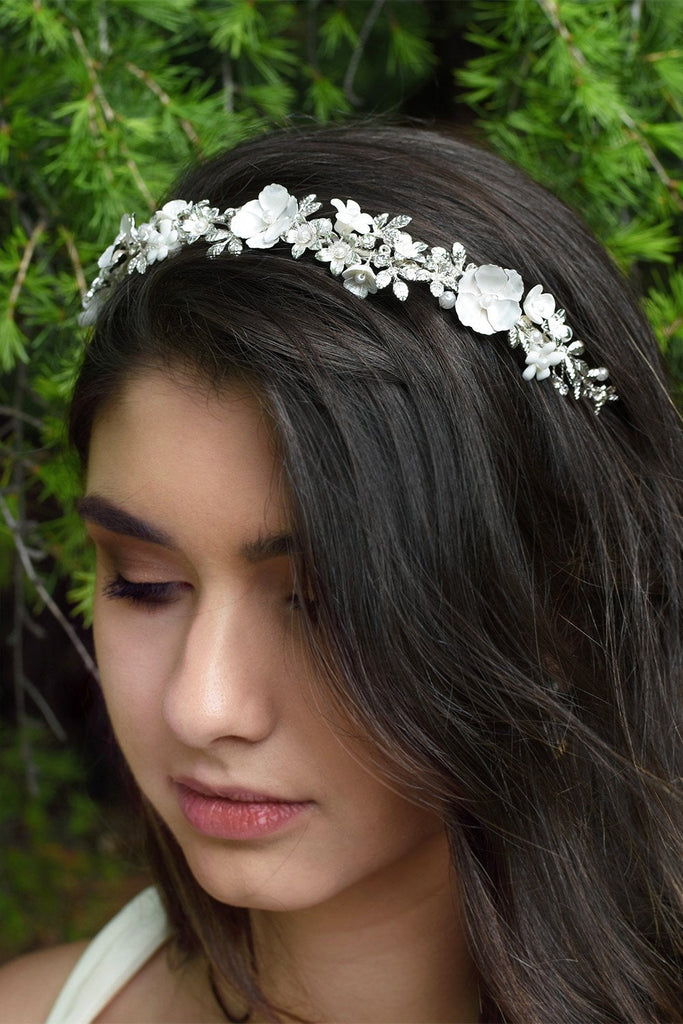 Dark hair model wearing a silver and flowers bridal headband with a pine tree bsckground
