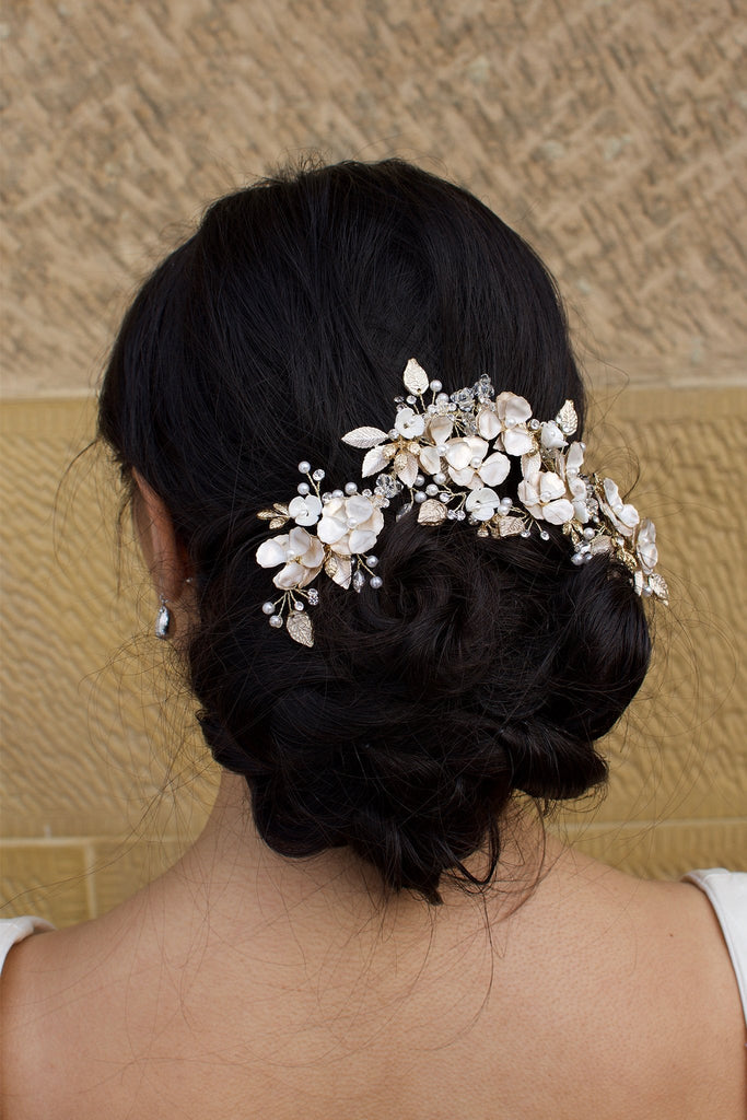Model Bride wears a Pale Gold Bridal Vine on her dark hair with a wall as background